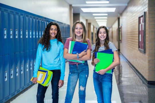 Three middle school girls standing in a school hallway